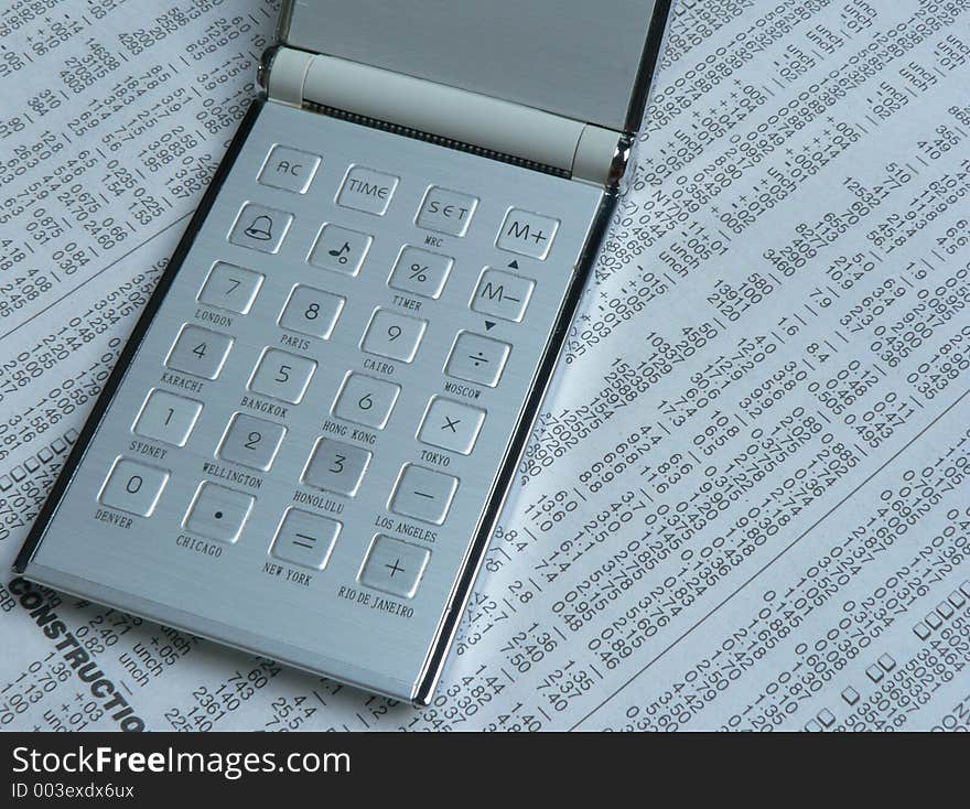 Shot of a calculator with name of cities printed on it, on a numerical newspaper background. Shot of a calculator with name of cities printed on it, on a numerical newspaper background.