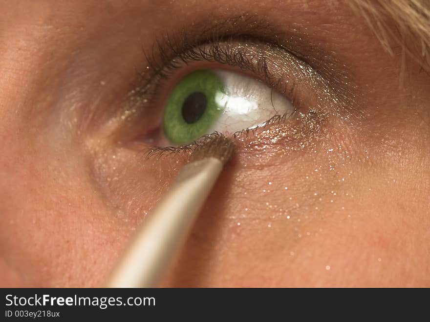 Woman with green eyes painting her eyeline. Woman with green eyes painting her eyeline