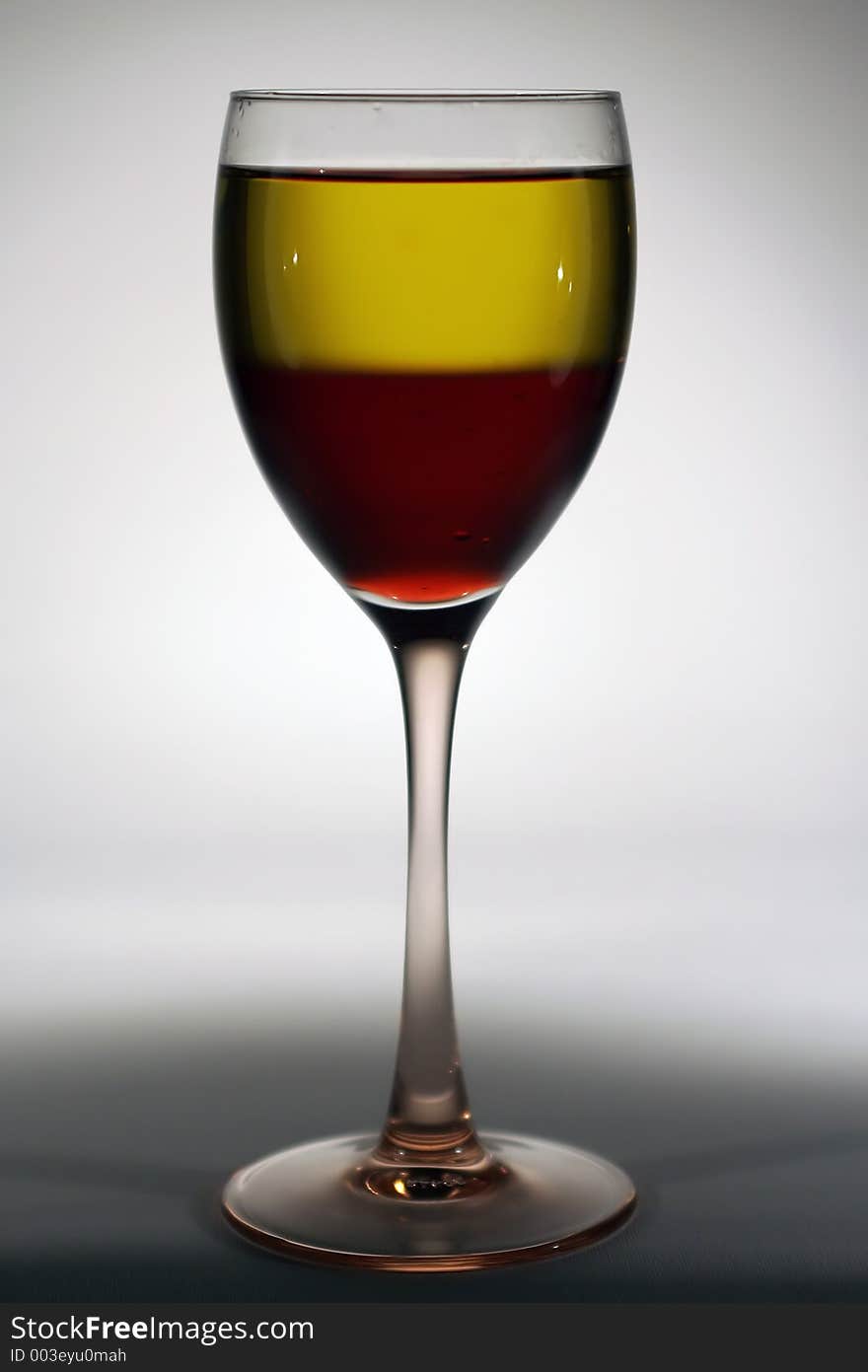 A glass of wine with white and red wines in it. A glass of wine with white and red wines in it.