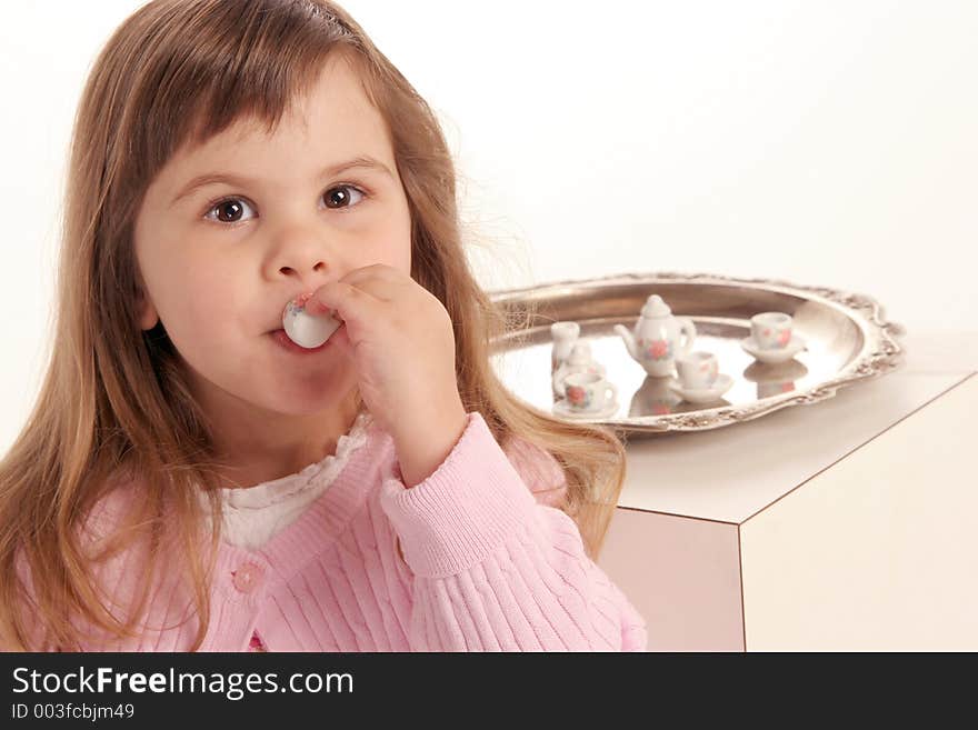 Young girl takes a sip of her tea at the tea party. Young girl takes a sip of her tea at the tea party