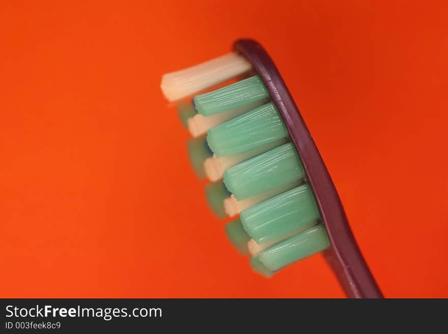 Macro of toothbrush leaning slightly isolated on orange background. Macro of toothbrush leaning slightly isolated on orange background