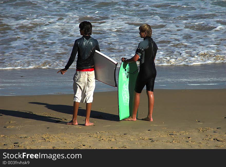 Two young boys with their boards ready to head out to the surf. Two young boys with their boards ready to head out to the surf