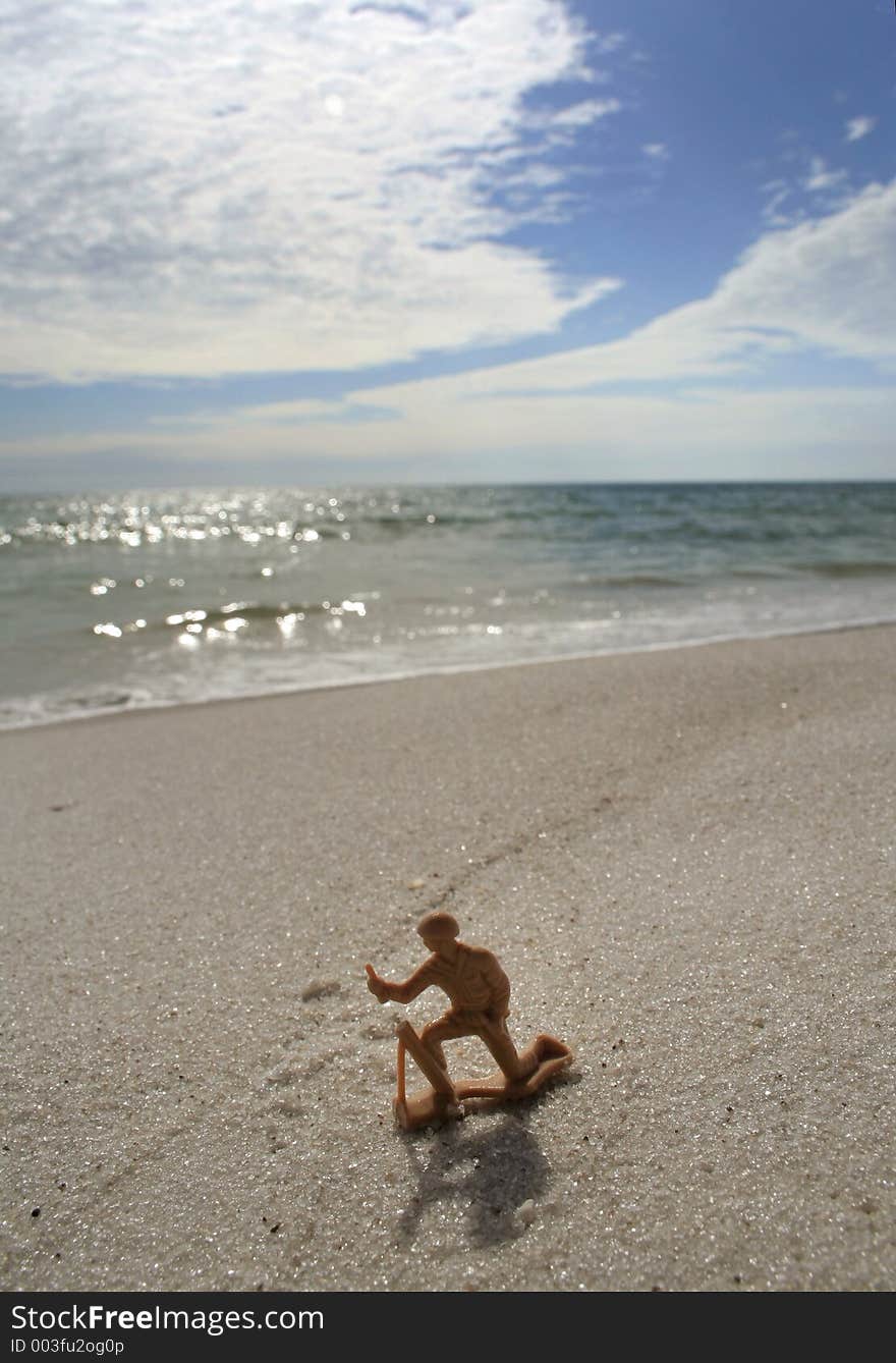 Plastic toy soldier on beach backlit near sun down. Plastic toy soldier on beach backlit near sun down