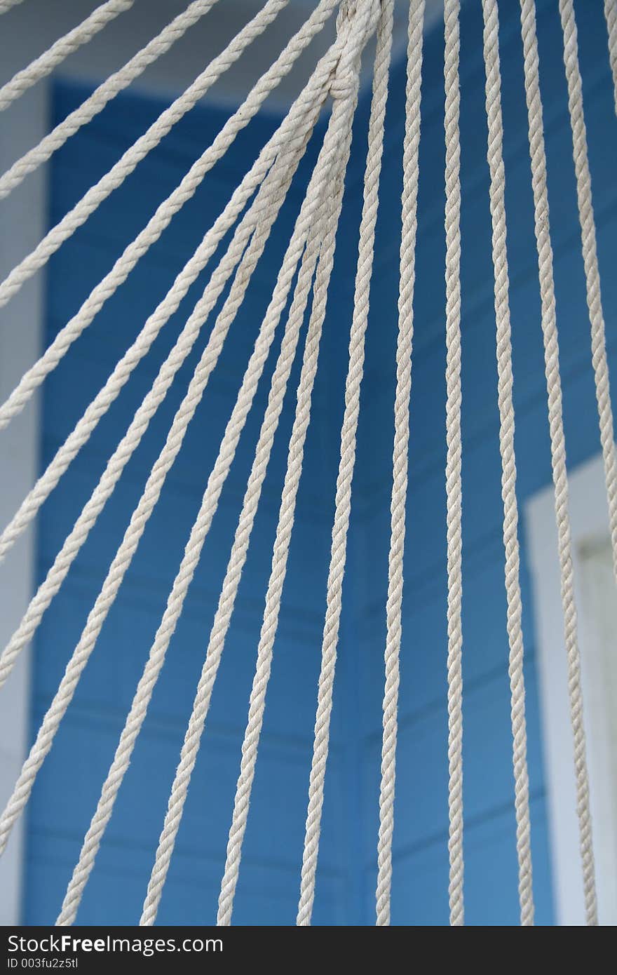 White ropes of a hammock against bright blue