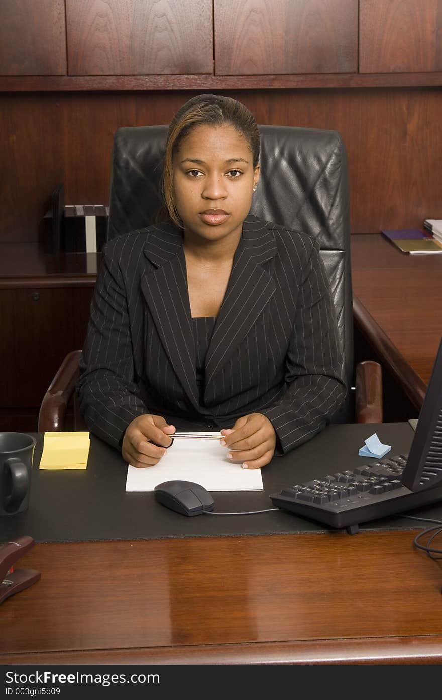 Young woman behind executive desk looking confident and ready for business. Young woman behind executive desk looking confident and ready for business