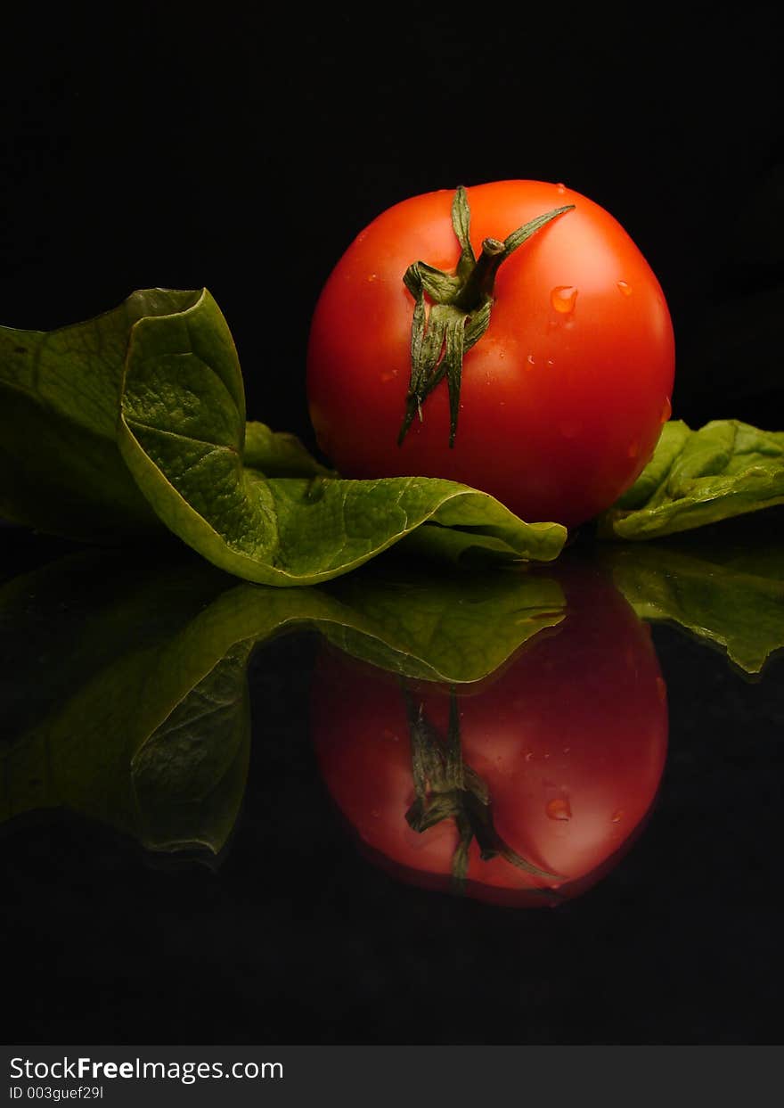 Tomato and salat on black and shine background. Tomato and salat on black and shine background