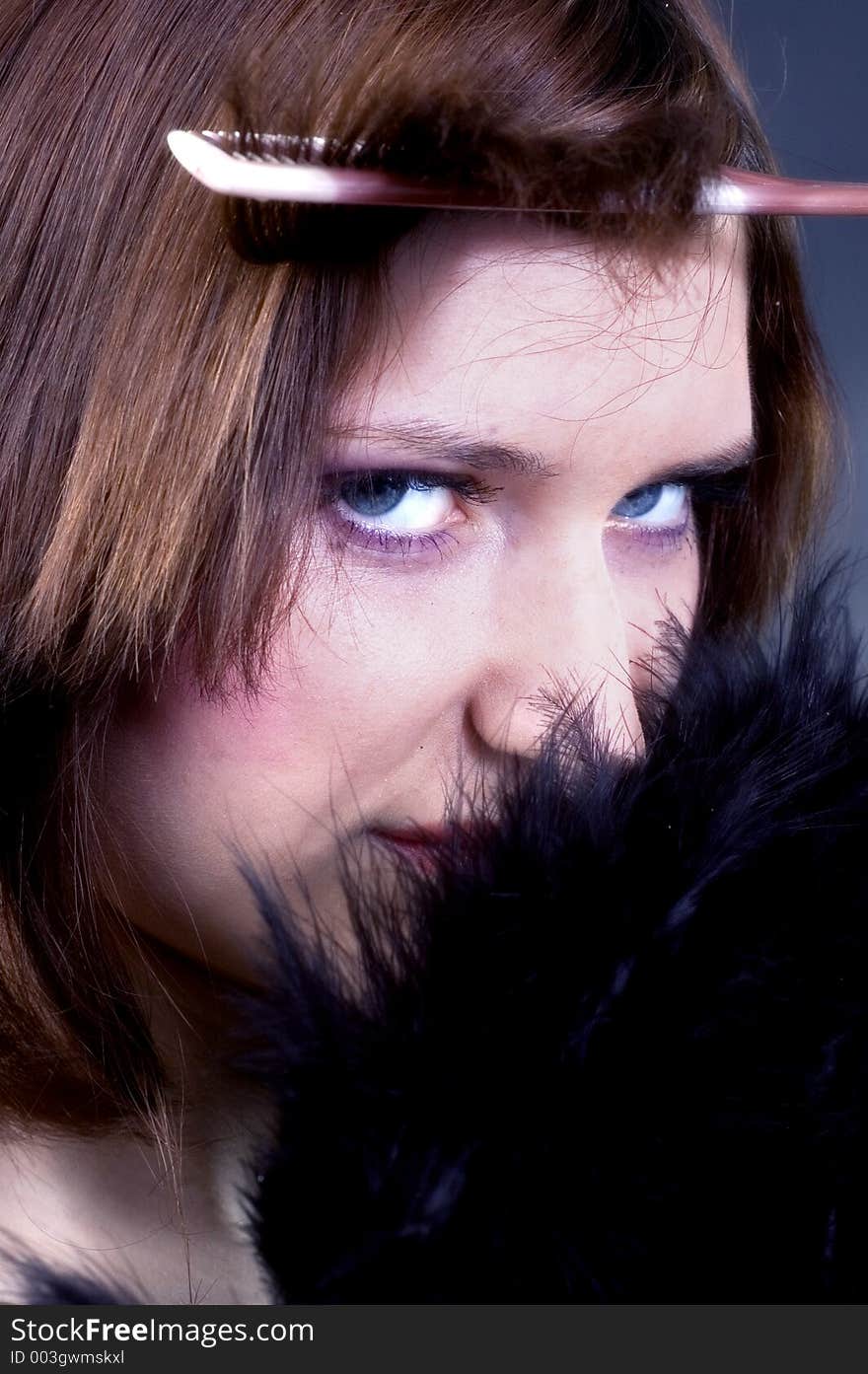 Young woman doing her hair and black feathers. Young woman doing her hair and black feathers