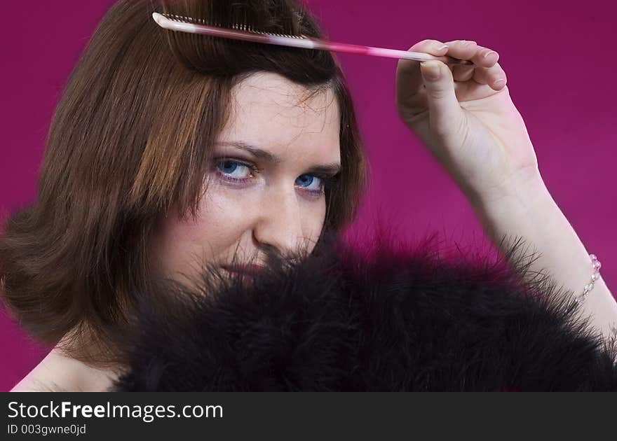 Young girl creating a hair style and black feathers on purple background