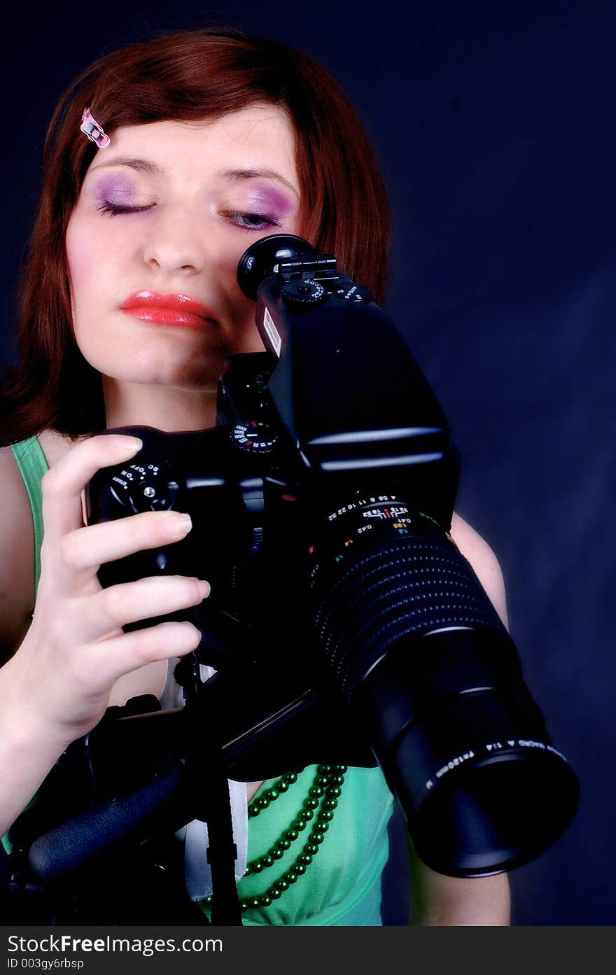 Young woman with great make-up playing with a studio camera. Young woman with great make-up playing with a studio camera