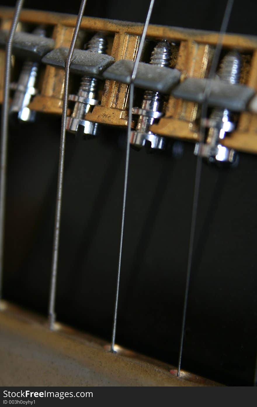 Close up image of the strings and nuts on an old fashioned black electric guitar - extreme mechanical close up. Close up image of the strings and nuts on an old fashioned black electric guitar - extreme mechanical close up