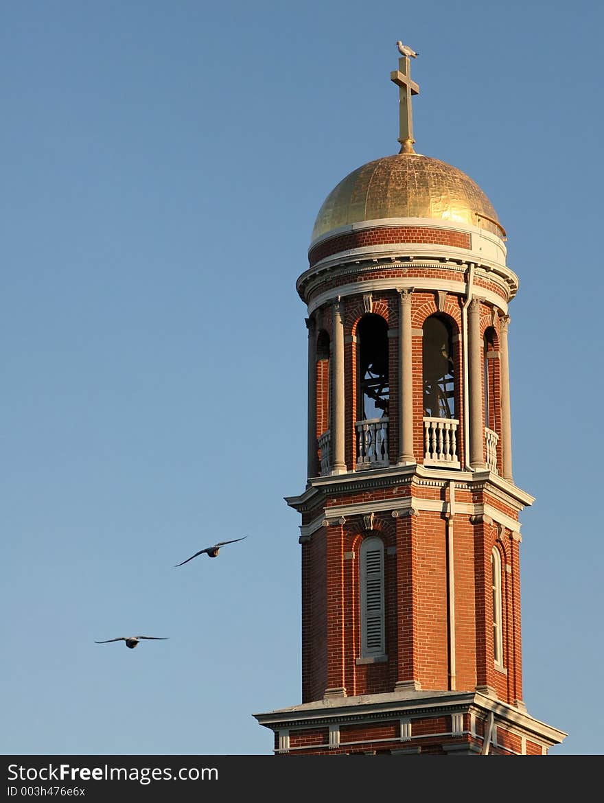 Birds flying by a church bell tower