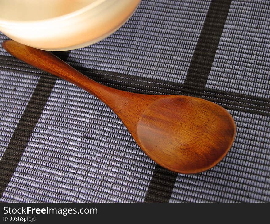 Oriental still life with a wooden spoon and a bowl on a blue material