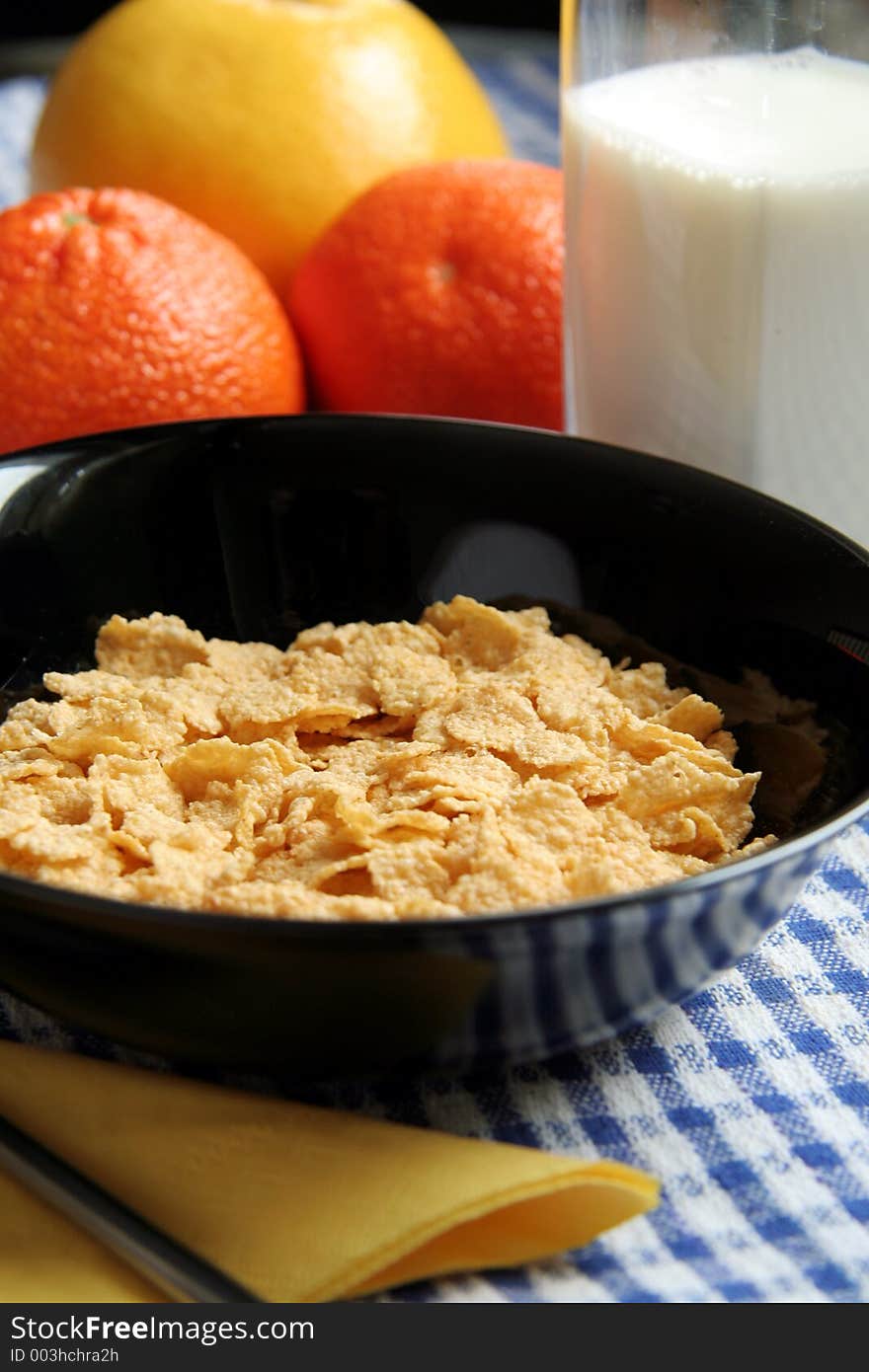 Picture of a corn flakes in a black bowl, milk and fruits. Picture of a corn flakes in a black bowl, milk and fruits