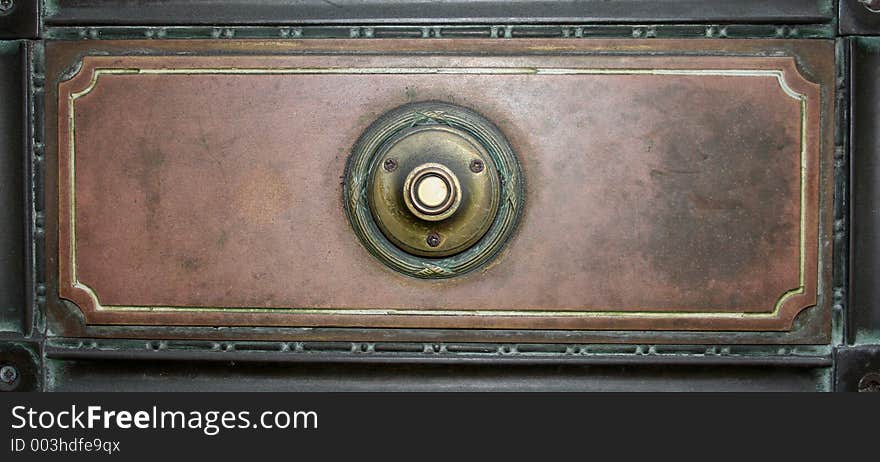 Image of an old fashioned door bell on a metal plate. Image of an old fashioned door bell on a metal plate