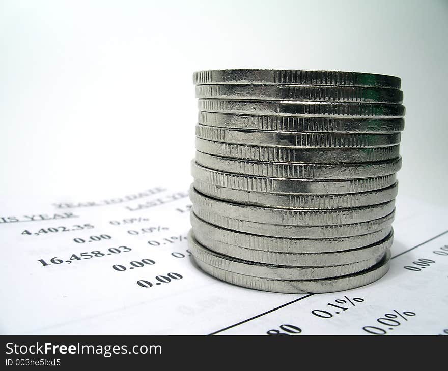 Coins on top of a financial report. Shallow depth of field. Focus on the coins. Coins on top of a financial report. Shallow depth of field. Focus on the coins.