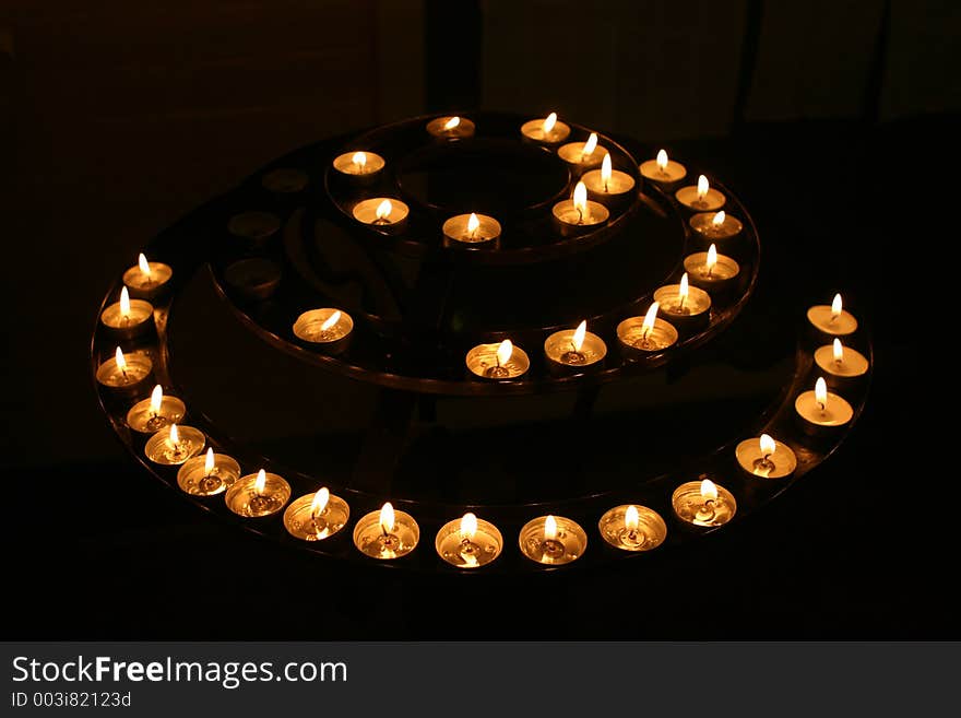 A concentric circle of candles gutters in a church at night. A concentric circle of candles gutters in a church at night