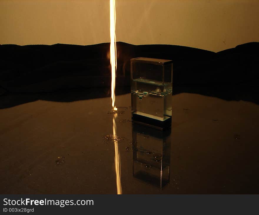 Burning candle drop beside standing object on glass background. Burning candle drop beside standing object on glass background