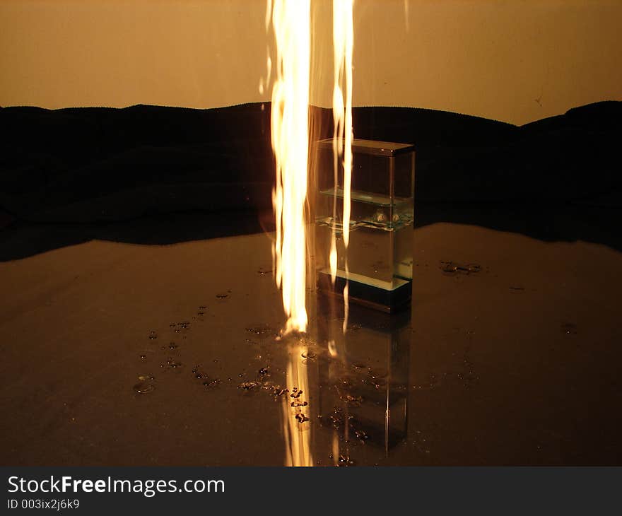 Burning candle drops beside object like sand clock. Burning candle drops beside object like sand clock