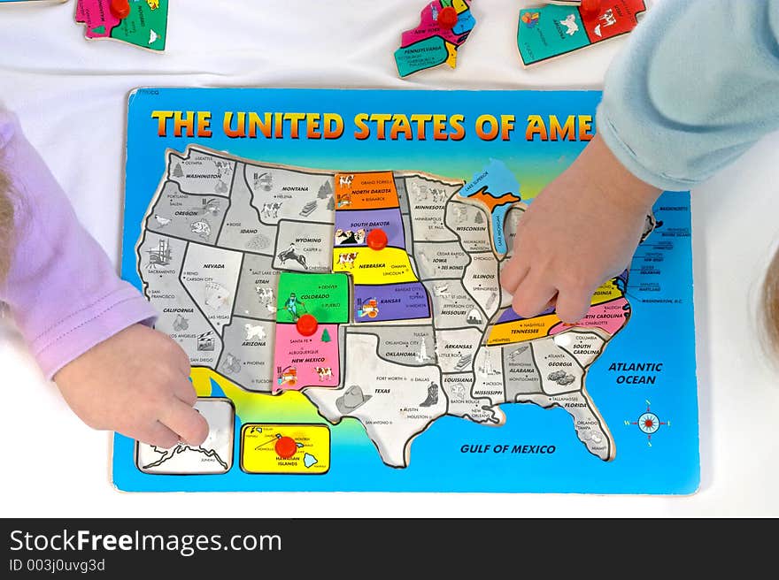 Two children putting together a wooden puzzle of the United States. Two children putting together a wooden puzzle of the United States