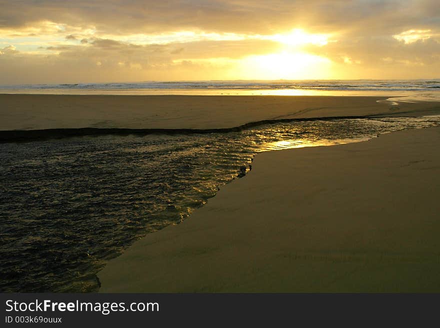 Texure and ripples on the top of a river of erosion running across a beach and into the ocean at sunset. Texure and ripples on the top of a river of erosion running across a beach and into the ocean at sunset.