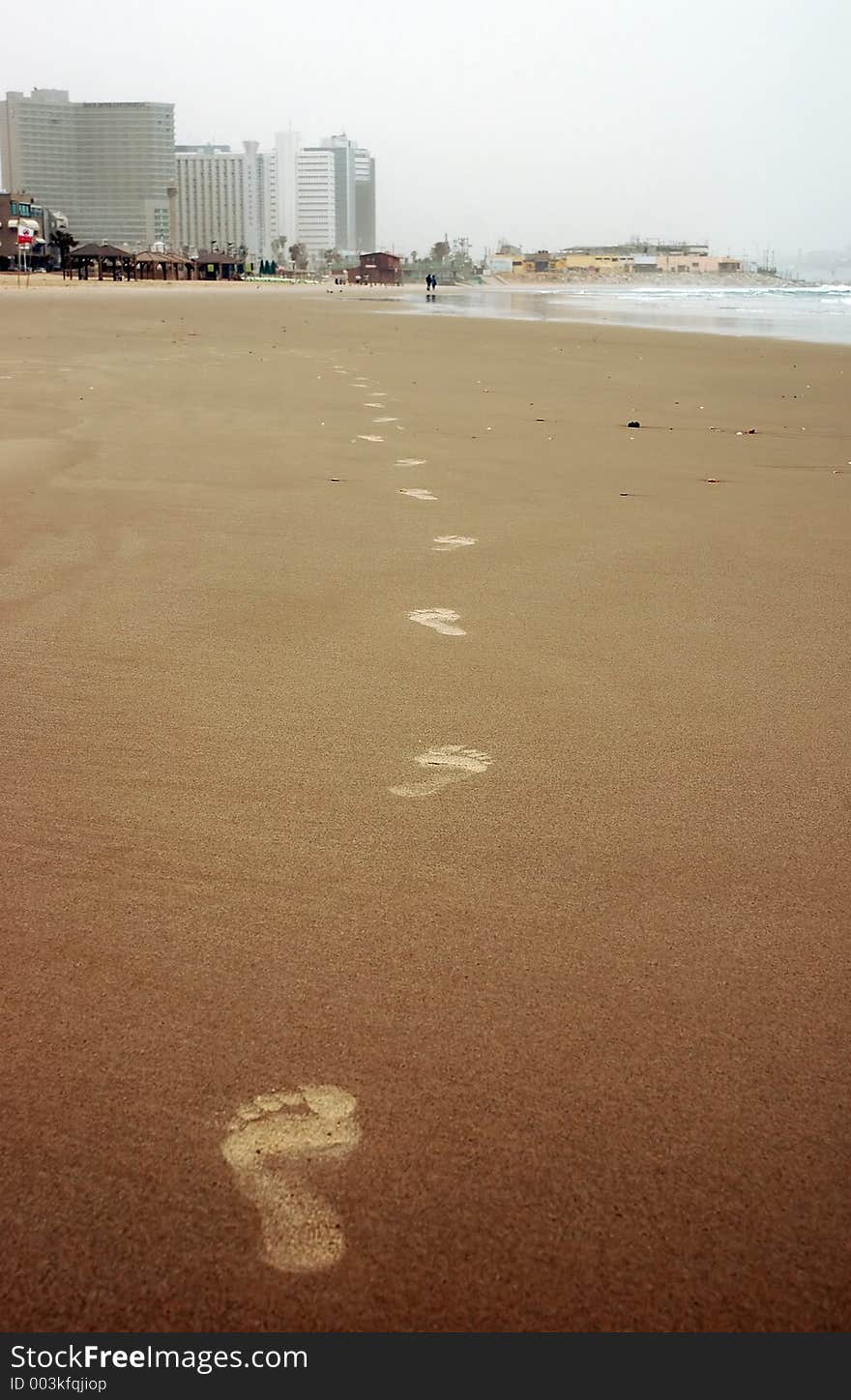 Barefoot prints on sand of winter beach