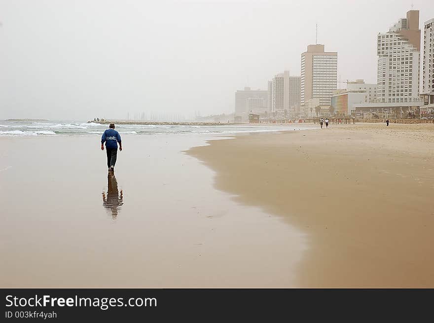 Elderly man enjoying a walk on empty winter beach in bad weather. Elderly man enjoying a walk on empty winter beach in bad weather