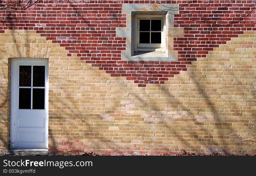 A door and window in a red and tan brick wall