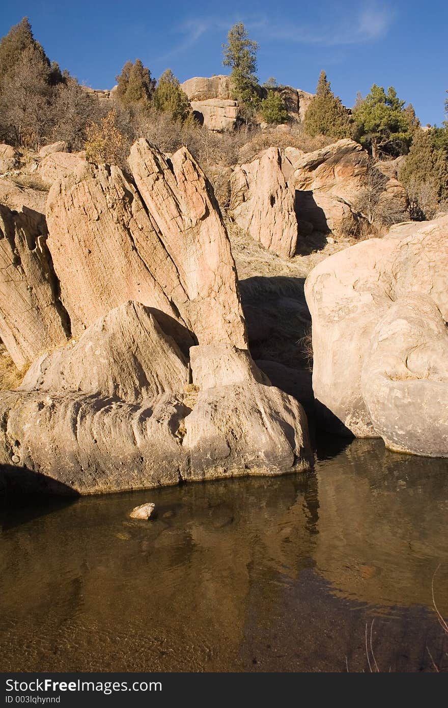 Unusual rock formations loom over a clear, calm pool of water in Castlewood Canyon of central Colorado. Unusual rock formations loom over a clear, calm pool of water in Castlewood Canyon of central Colorado.