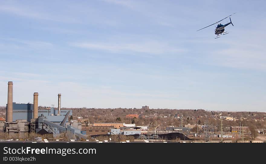 A blue and white police helicopter patrols over the power plant in downtown Colorado Springs. A blue and white police helicopter patrols over the power plant in downtown Colorado Springs