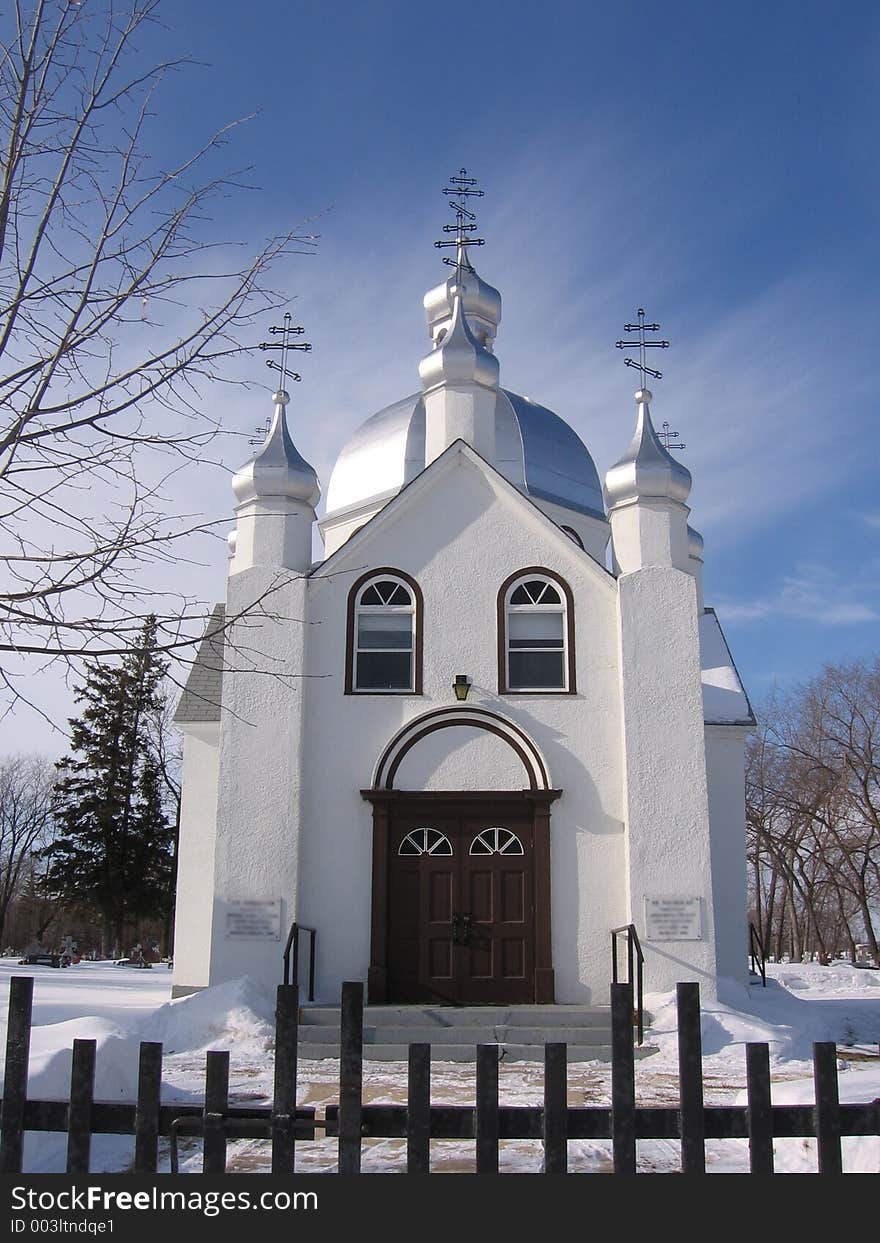 This image depicts a small church with silver domes in the winter season.