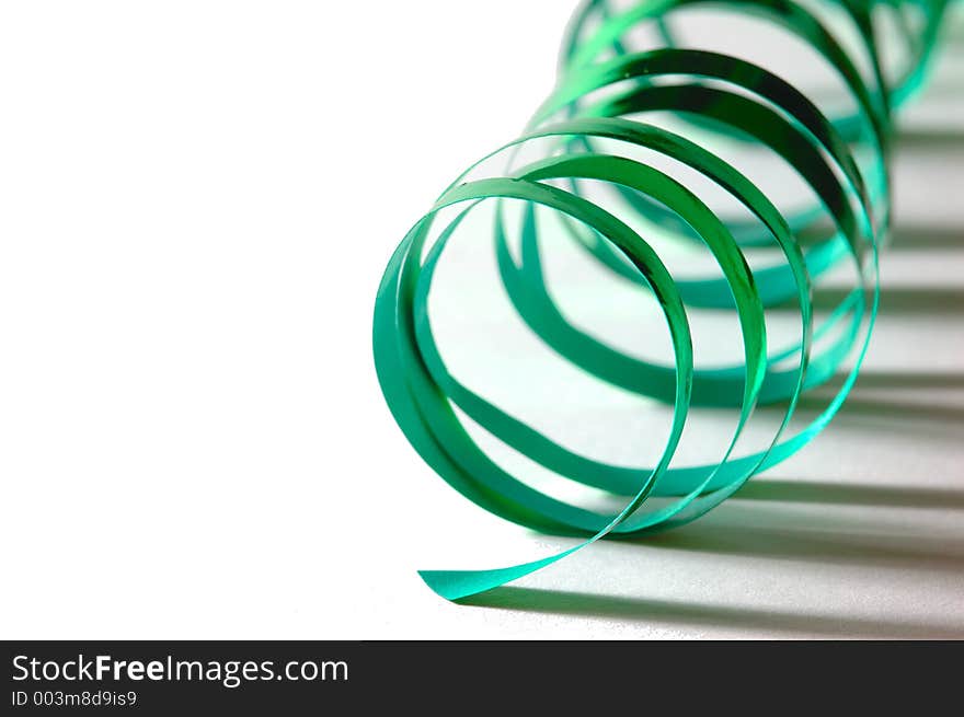 A curly green ribbon on white ground with shadows