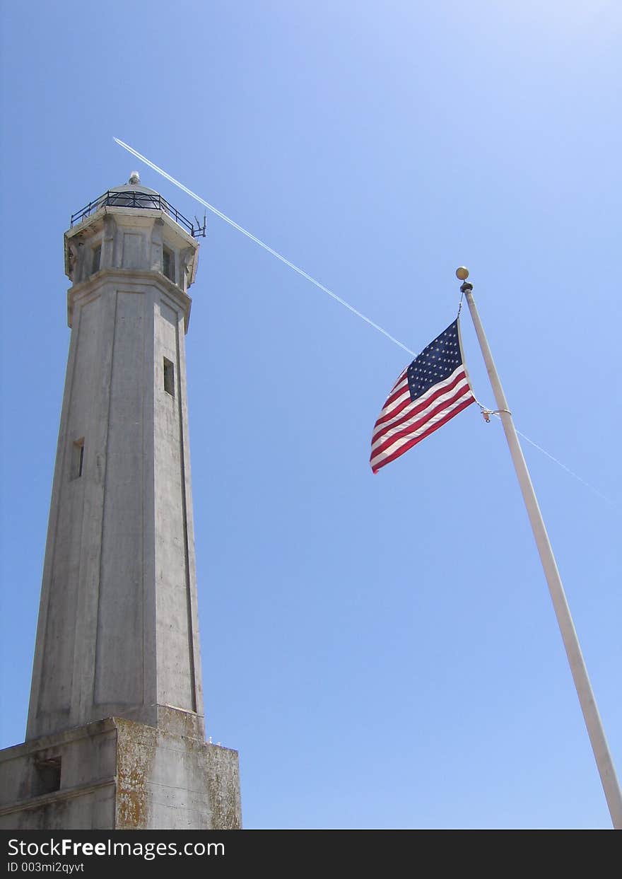 Alcatraz lighthouse and American flag on a pole.