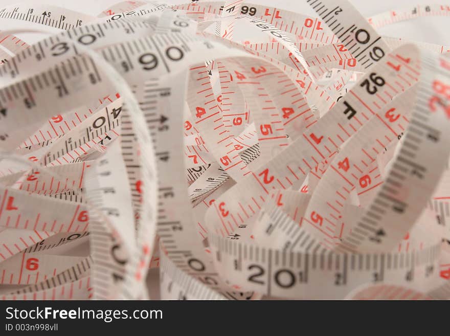 Long synthetic tape measure all bunched up. Metric and imperial markings. Long synthetic tape measure all bunched up. Metric and imperial markings.