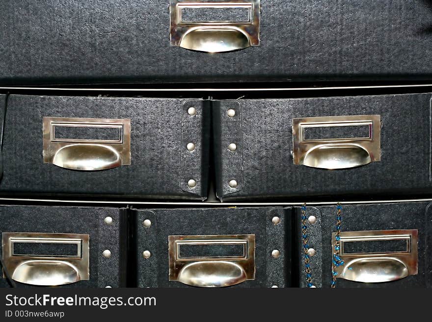 Black paper drawers with little necklace hanging out of right lower one. Black paper drawers with little necklace hanging out of right lower one