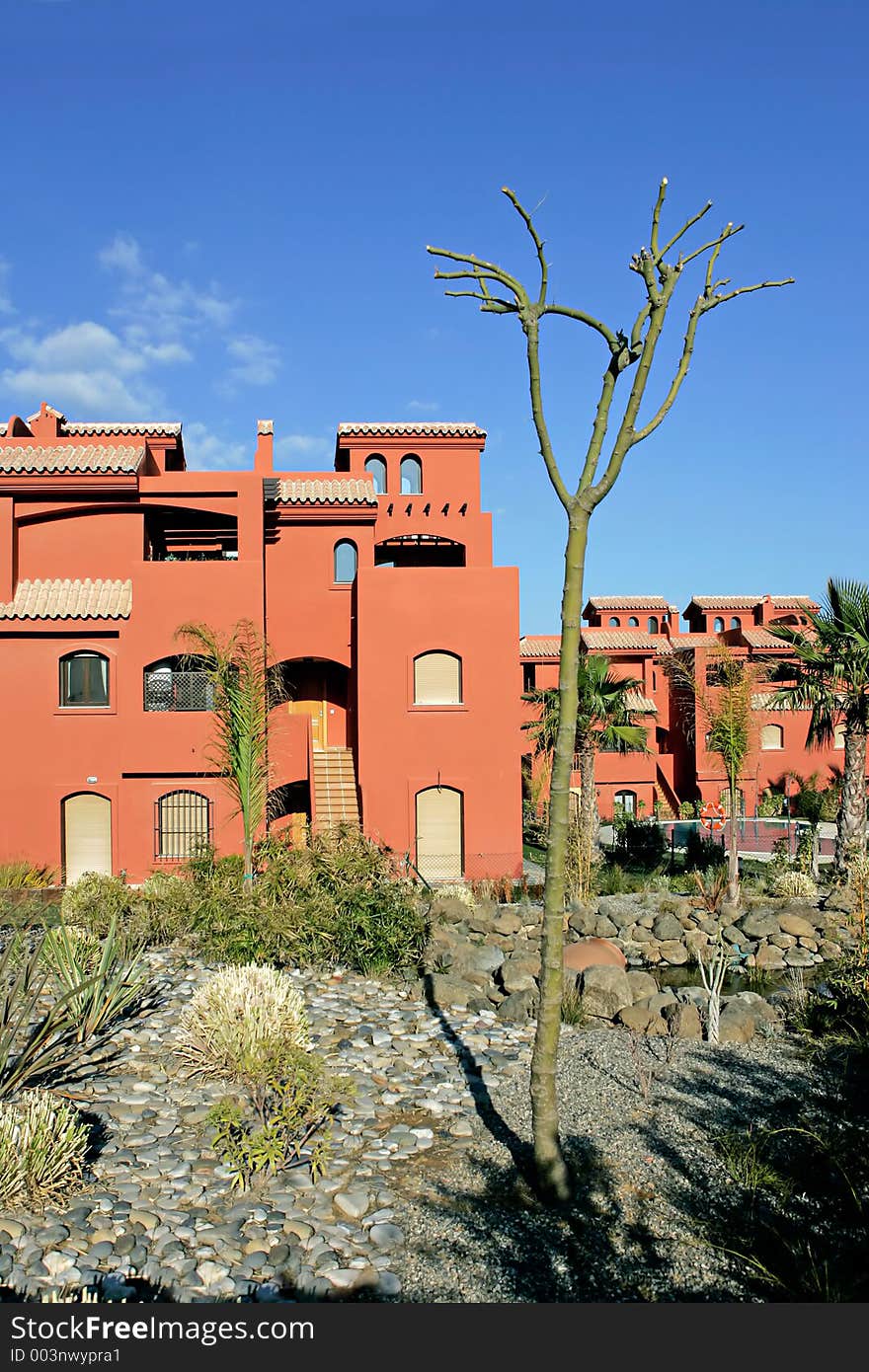 Salmon or orange apartments on Spanish urbanization on the Costa del Sol in Spain with sunny blue sky. Salmon or orange apartments on Spanish urbanization on the Costa del Sol in Spain with sunny blue sky