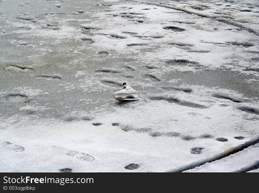 An abandoned white skating shoe in a frozen lagoon. An abandoned white skating shoe in a frozen lagoon.