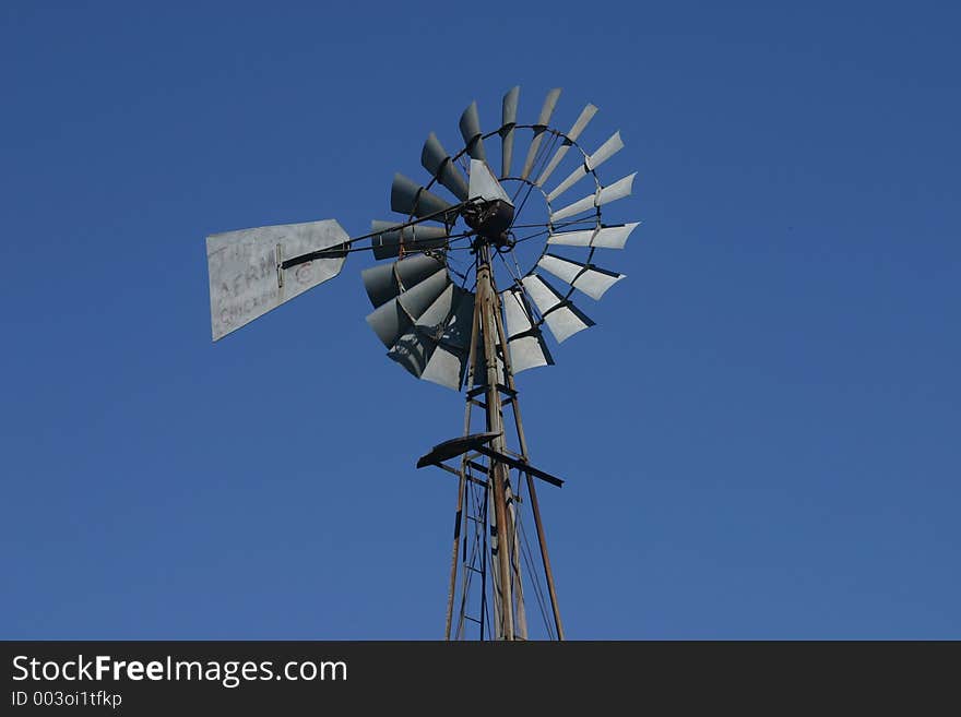 A rustic windmill set against a clear blue sky