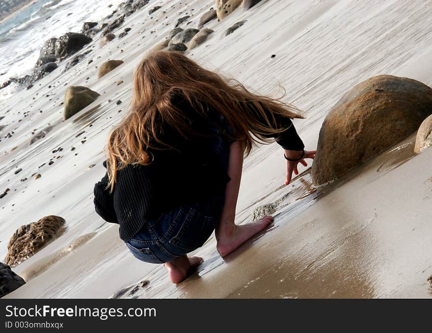 Young girl drawing in the wet sand at the beach. Young girl drawing in the wet sand at the beach