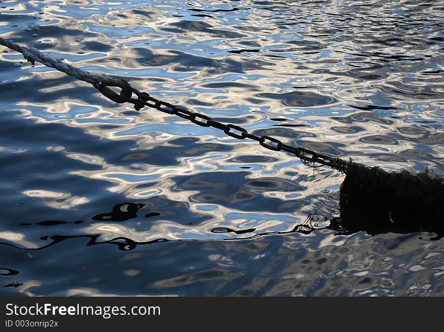 Boat chain silhouette against ocean water, seaweed tangled around the chain. Boat chain silhouette against ocean water, seaweed tangled around the chain