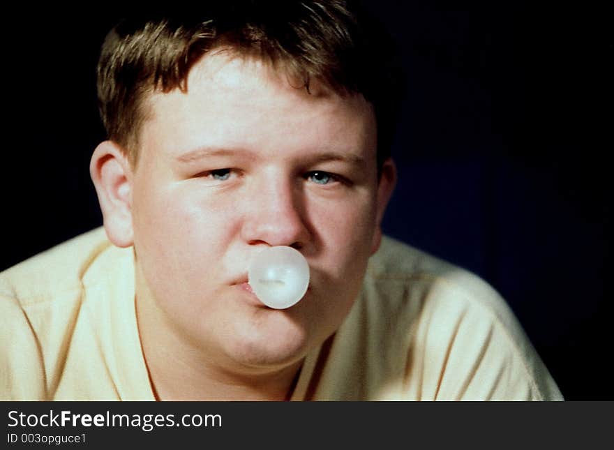 Teenage boy blowing a bubble with gum. Teenage boy blowing a bubble with gum.