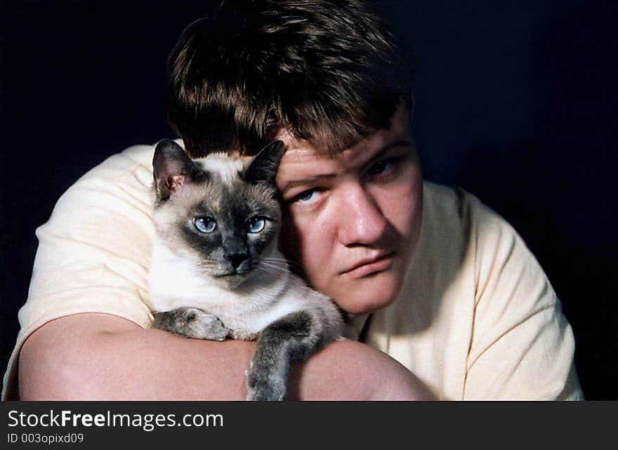 Teenage boy holding Siamese cat. Teenage boy holding Siamese cat.