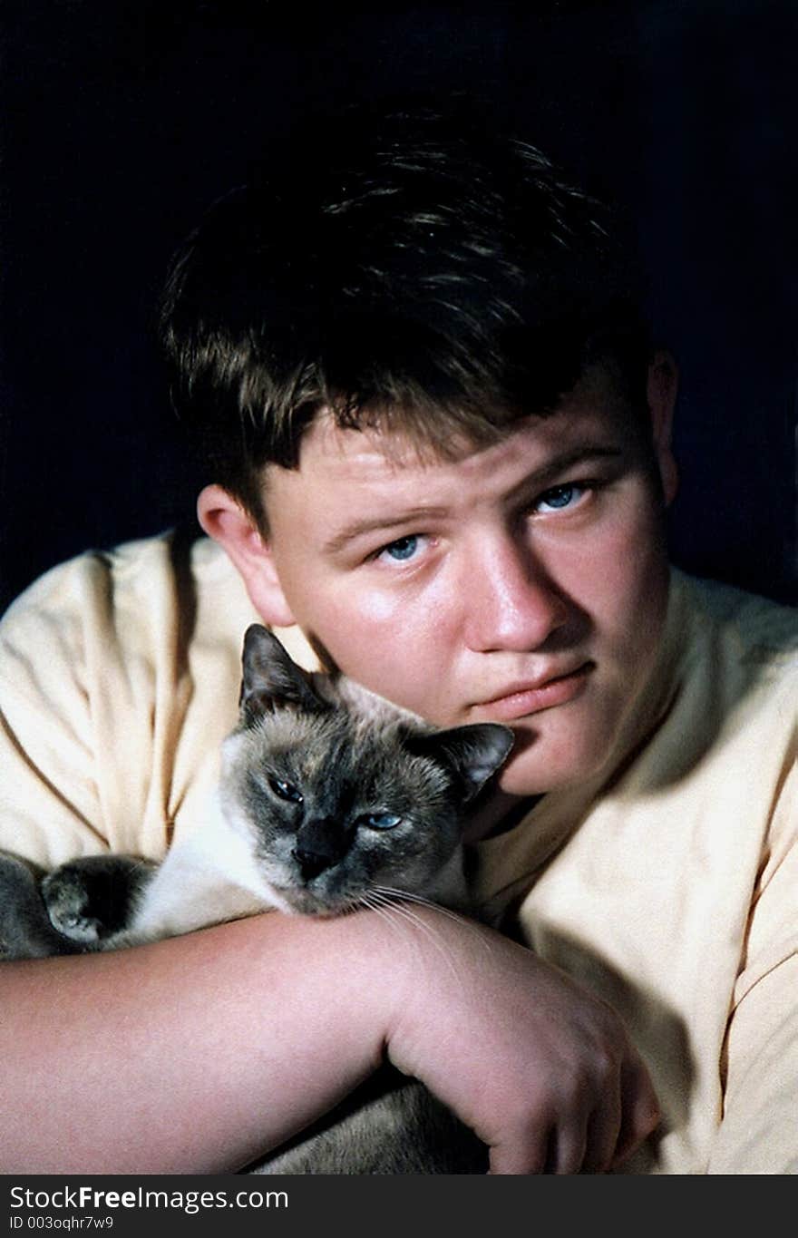 Teenage boy holding a Siamese cat. Teenage boy holding a Siamese cat.