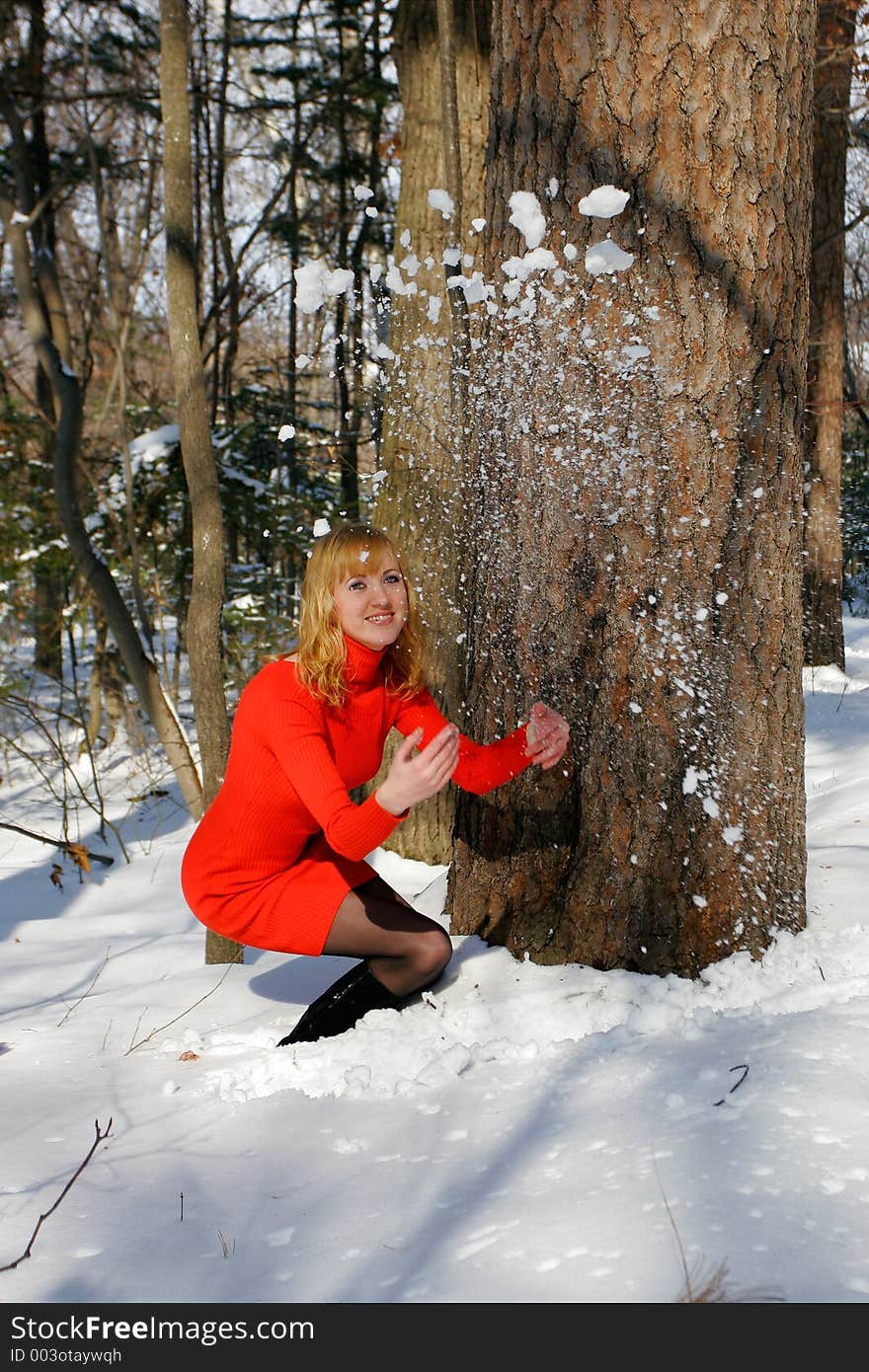 The young beautiful girl in a wood throws a snow