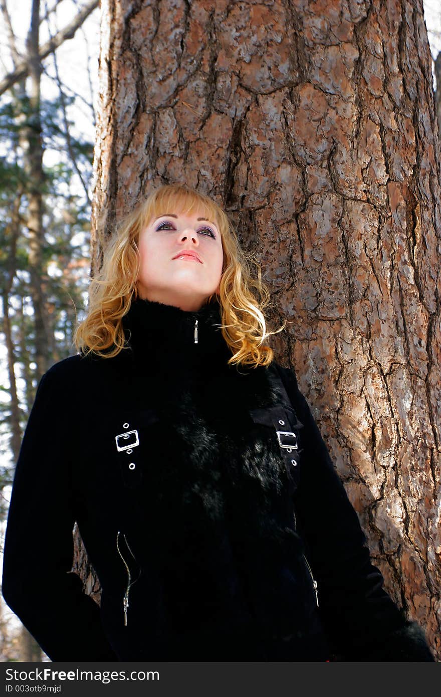 The young beautiful girl in a wood stands near a tree