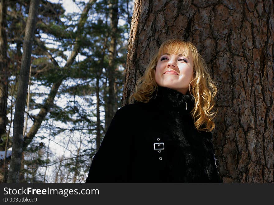 The young beautiful girl in a wood stands near a tree