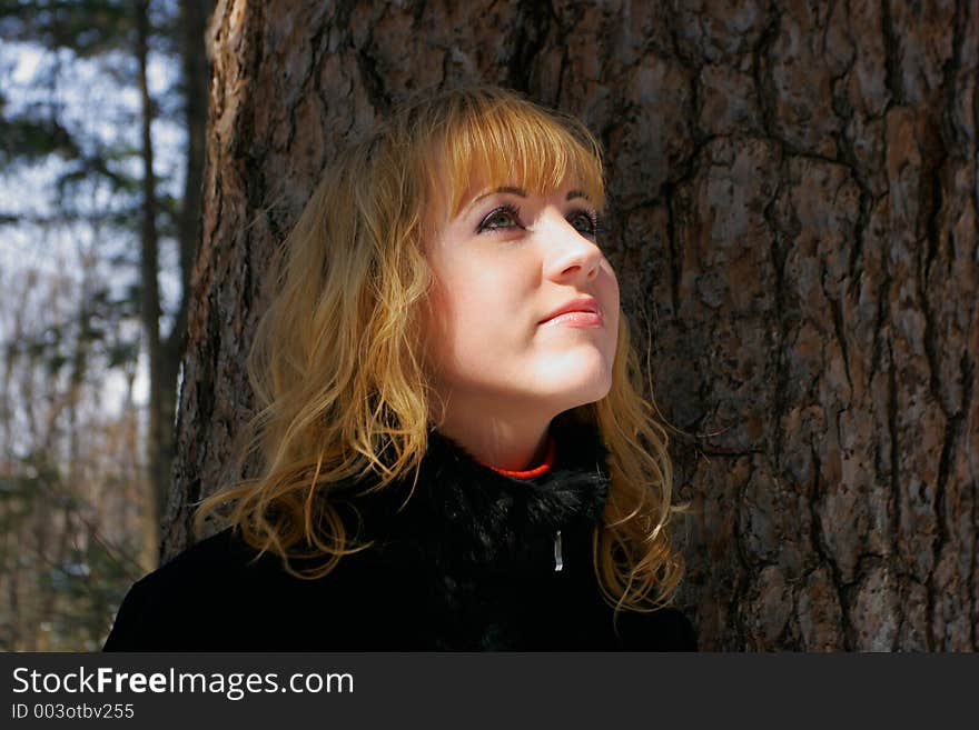 The young beautiful girl in a wood stands near a tree