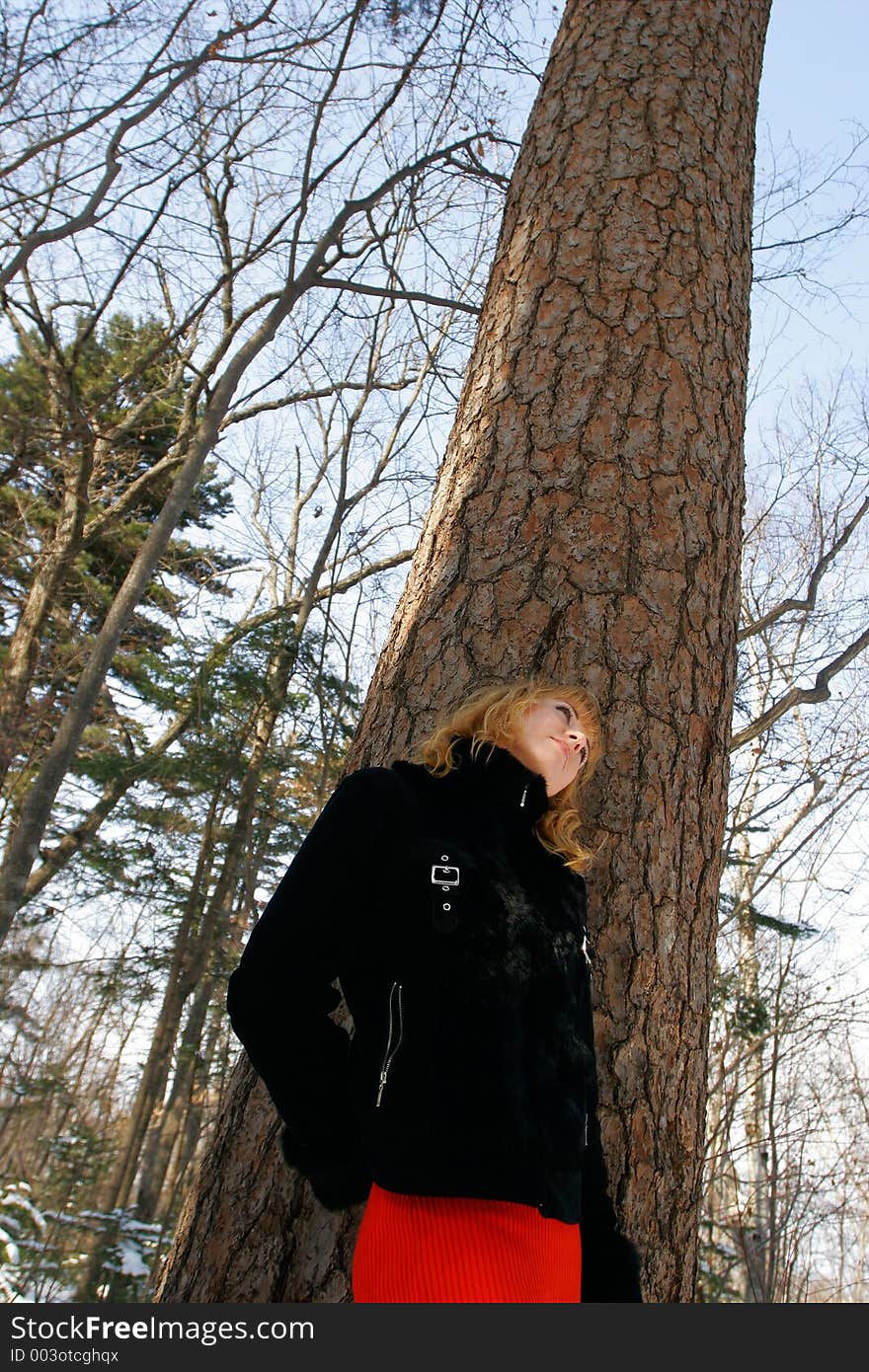 The young beautiful girl in a wood stands near a tree