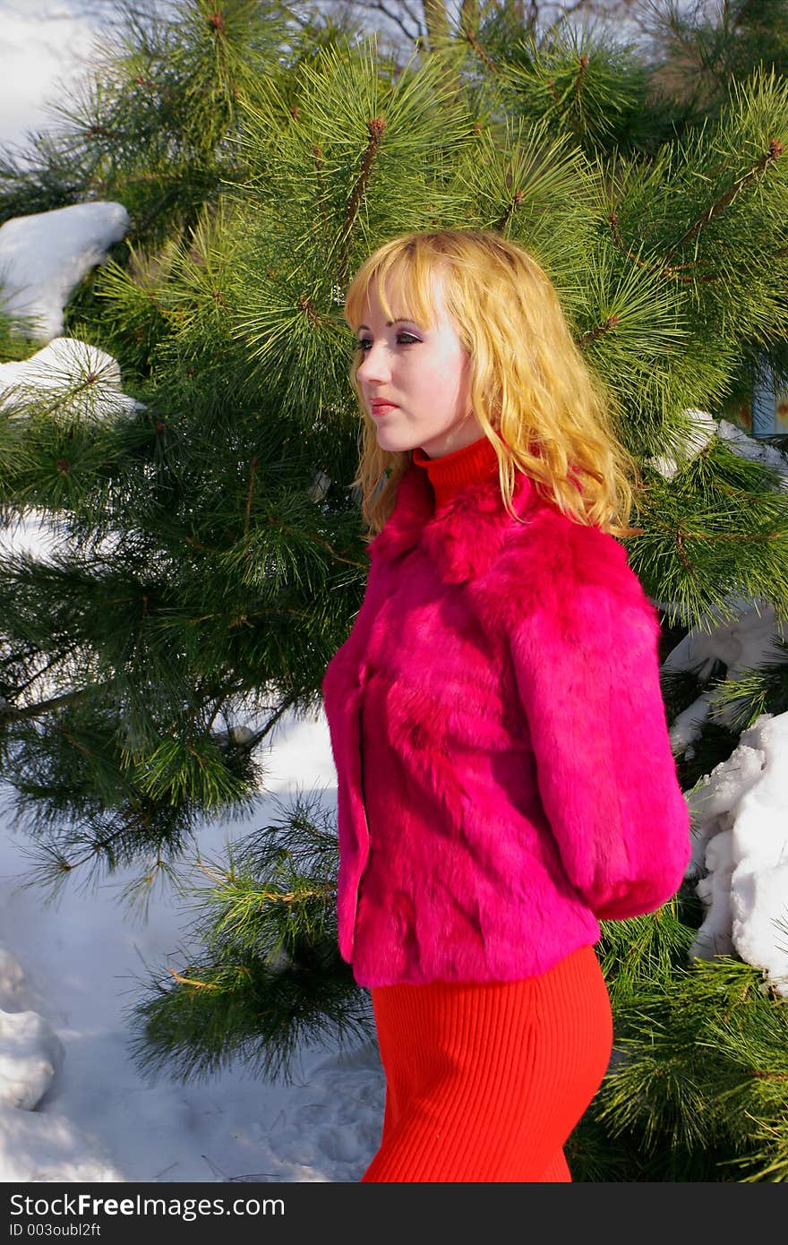 The young beautiful girl in a wood stands near a tree