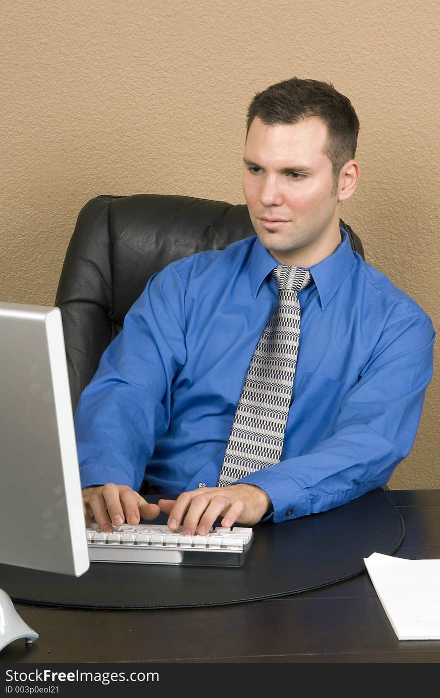 Office clerk deeply involved in a web chatting looks on the monitor seriously, concentrated on writing. Office clerk deeply involved in a web chatting looks on the monitor seriously, concentrated on writing