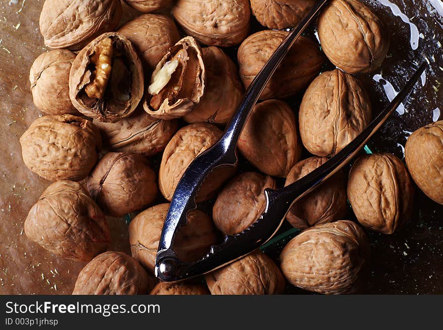 Walnuts and a cracker on a glass plate. One nut open. Walnuts and a cracker on a glass plate. One nut open.